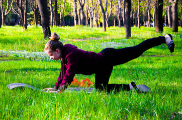 The girl on the street in the karemat practices sports and yoga. The girl goes in for sports in the  forest