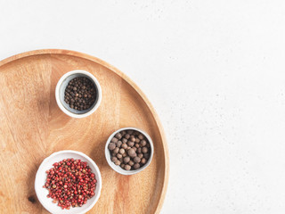 Kitchen minimalism concept. Various spices in small bowl on wood tray on light background. Top view. Copy space