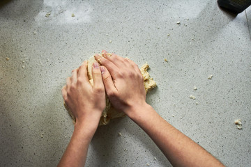 hands kneading bread on white table