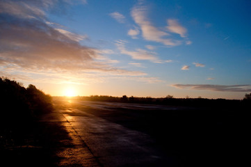 Sun rises over a dark disused runway.