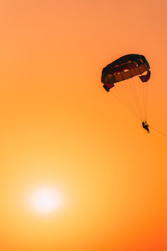 Parasailers Flying On Colorful Parachute In Sunset Sunrise Sky. Active Hobby. Sunshine