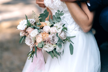 wedding bouquet in the hands of the bride with white roses and pink flowers green leaves eucalyptus with pink ribbon decor