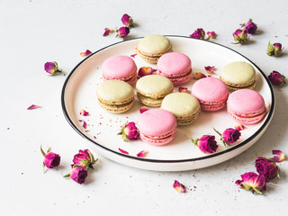Creative composition of sweet macaron cookies on plate and dry flowers on light background 