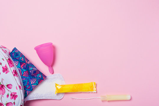 Copa menstrual de silicona. Neceser con art&iacute;culos de higiene &iacute;ntima para la menstruaci&oacute;n como compresa, tamp&oacute;n y copa menstrual. Salud de la mujer e higiene alternativa. Fondo rosa