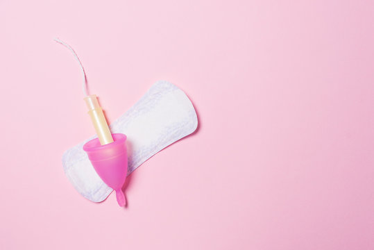 Copa menstrual de silicona, compresa y tamp&oacute;n para la menstruaci&oacute;n. Salud de la mujer e higiene alternativa. Fondo rosa