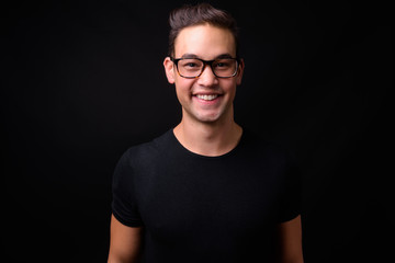 Young handsome multi ethnic man against black background