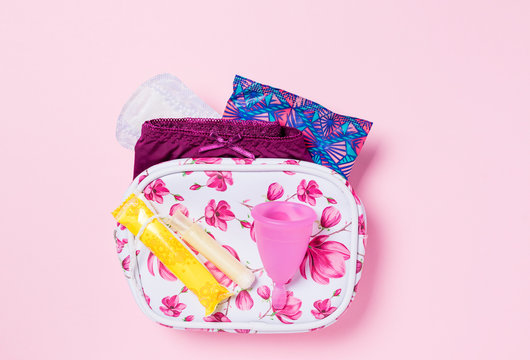 Copa menstrual de silicona. Neceser con art&iacute;culos de higiene &iacute;ntima para la menstruaci&oacute;n como compresa, tamp&oacute;n y copa menstrual. Salud de la mujer e higiene alternativa. Fondo rosa