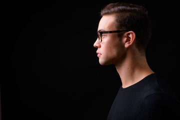 Young handsome multi ethnic man against black background
