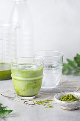 matcha tea with ice and milk in a glass on a grey background