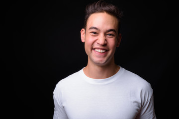 Young handsome multi ethnic man against black background