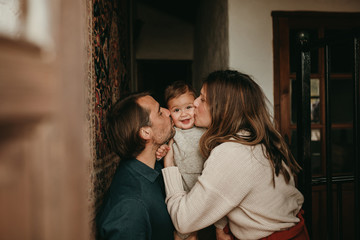 Lovely baby infant being kissed by mom and dad at home.