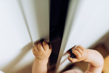 Kinderhände öffnen weiße Schranktür 