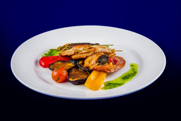 Turkey medallions stuffed with herbs on skewers with grilled vegetables and pesto sauce on a white...
