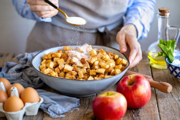 Add sugar to the pie filling. The girl pours sugar into the apple strudel filling. Sugar sprinkles...