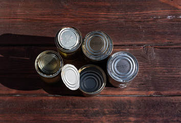 old empty cans on a wooden table, brown wooden background