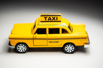 Urban taxi and delivery service concept. Toy yellow taxi car model.