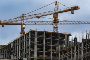 Construction site with cranes. High-rise construction cranes and a lot of unfinished buildings. Construction of multi-apartment modern houses and a new residential complex. Blue sky.
