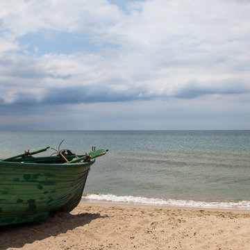 Old wooden green boat on the seashore.