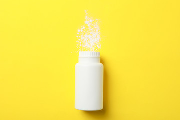Blank bottle of talcum powder on yellow background, space for text