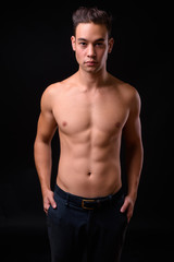 Fototapeta na wymiar Young handsome multi ethnic man shirtless against black background