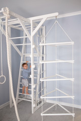 Portrait of little boy at the background of a ladder at home.