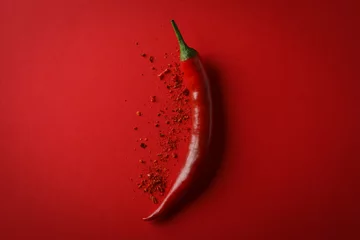 Leckere Chilischote und Gewürzpulver auf rotem Grund © Atlas