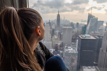 woman looking at the skyscrapers of New York City from a window