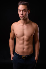 Fototapeta na wymiar Young handsome multi ethnic man shirtless against black background