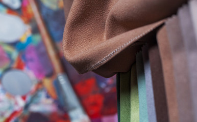 colorfull textile lies on a colorfull palette of the artist.Colored brushes and fabrics.