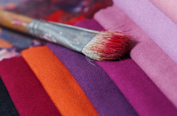 colorfull textile lies on a colorfull palette of the artist.Colored brushes and fabrics.