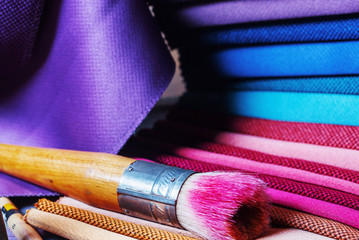 colorfull textile lies on a colorfull palette of the artist.Colored brushes and fabrics.