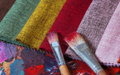 colorfull textile lies on a colorfull palette of the artist.Colored brushes and fabrics.
