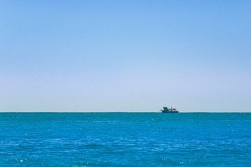 The ship sails on the horizon - blue sea and blue sky in summer.