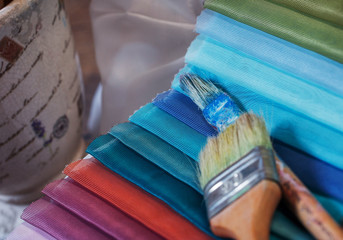 colorfull textile lies on a colorfull palette of the artist.Colored brushes and fabrics.