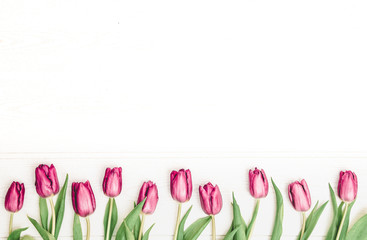 Rustic-styled spring flatlay with magenta tulips on a white plank background. Horizontal image with space for text or product.