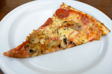 Slice of delicious thin crusted pepperoni mushroom pizza