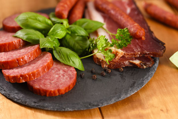 Ham and smoked sausage cutting on a slate plate. A snack in between.