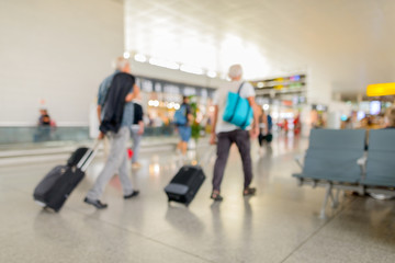 Defocused terminal departure check in at airport with walking travelers