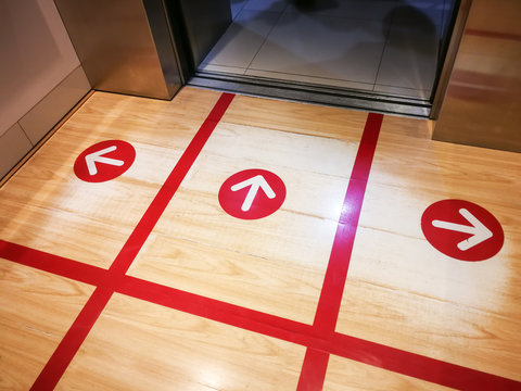 Red Tape On The Elevator Or Lift Floor With Arrow Sign For Direction Of Standing Position To Limit Or Control Number Of People Entry Into The Lift ,Social Distancing In COVID-19 Or Coronavirus Crisis