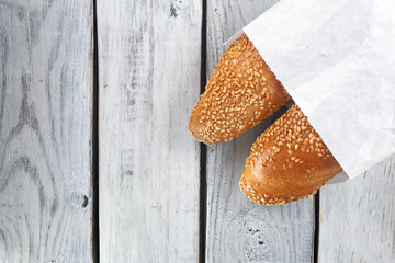 white bread baguette wrapped in white food paper on white wooden background top view