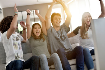 Group of friends cheering up as watching game on TV