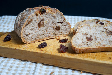 Slices of homemade bread with raisins, walnuts, spices and chopped nuts on beige and white tablecloth