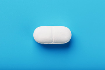 Medicinal tablet on a blue background, isolated.