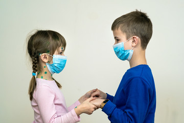 Boy and girl wearing blue protective medical mask ill with chickenpox, measles or rubella virus with rashes on body. Children protection during epidemic of coronovirus. Covid-19 contagion concept.