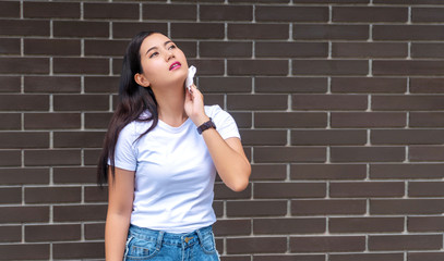 Attractive young woman long hair feeling very hot while standing on concrete walls background.Young...