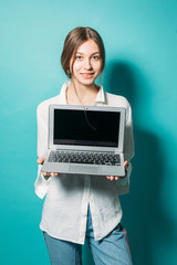 young girl in a white shirt and jeans with a laptop on a blue background