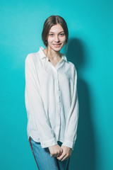 young girl in a white shirt and jeans with a laptop on a blue background in the studio