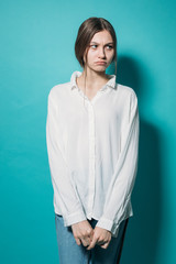 Fototapeta premium young girl in a white shirt and jeans with a laptop on a blue background in the studio