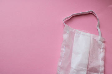 white disposable medical mask on a pink background