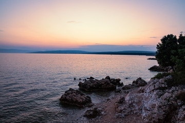 Abendstimmung am Meer im Vordergrund Felsen  der Himmel hat eine rot gelbe Färbung 